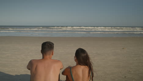 una pareja joven tomando el sol en la playa.