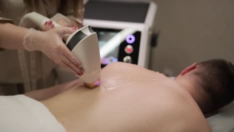 aesthetician perform laser hair removal on a man's back in a professional clinic