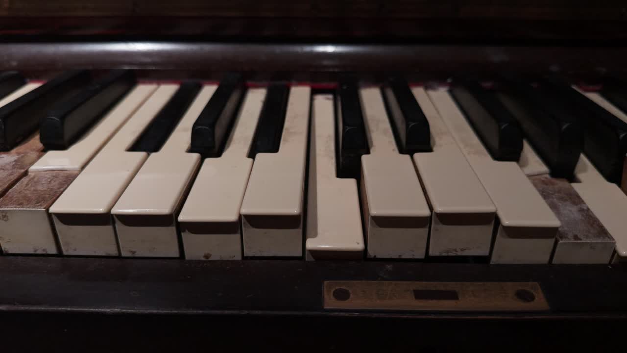 Primo piano di un pianoforte a rullo vintage con tasti d'avorio in movimento in una stanza di una villa infestata. Questo strumento meccanico crea un'atmosfera spettrale e soprannaturale per film horror, di mistero o in costume.