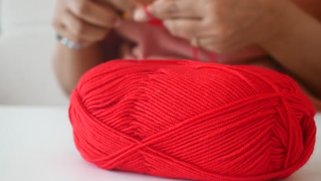 woman knitting with red yarn