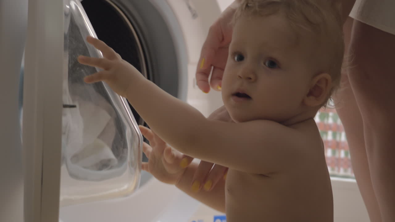 호기심 많은 아기 소녀 는 집안 일 을 하는 어머니 를 보고 있다