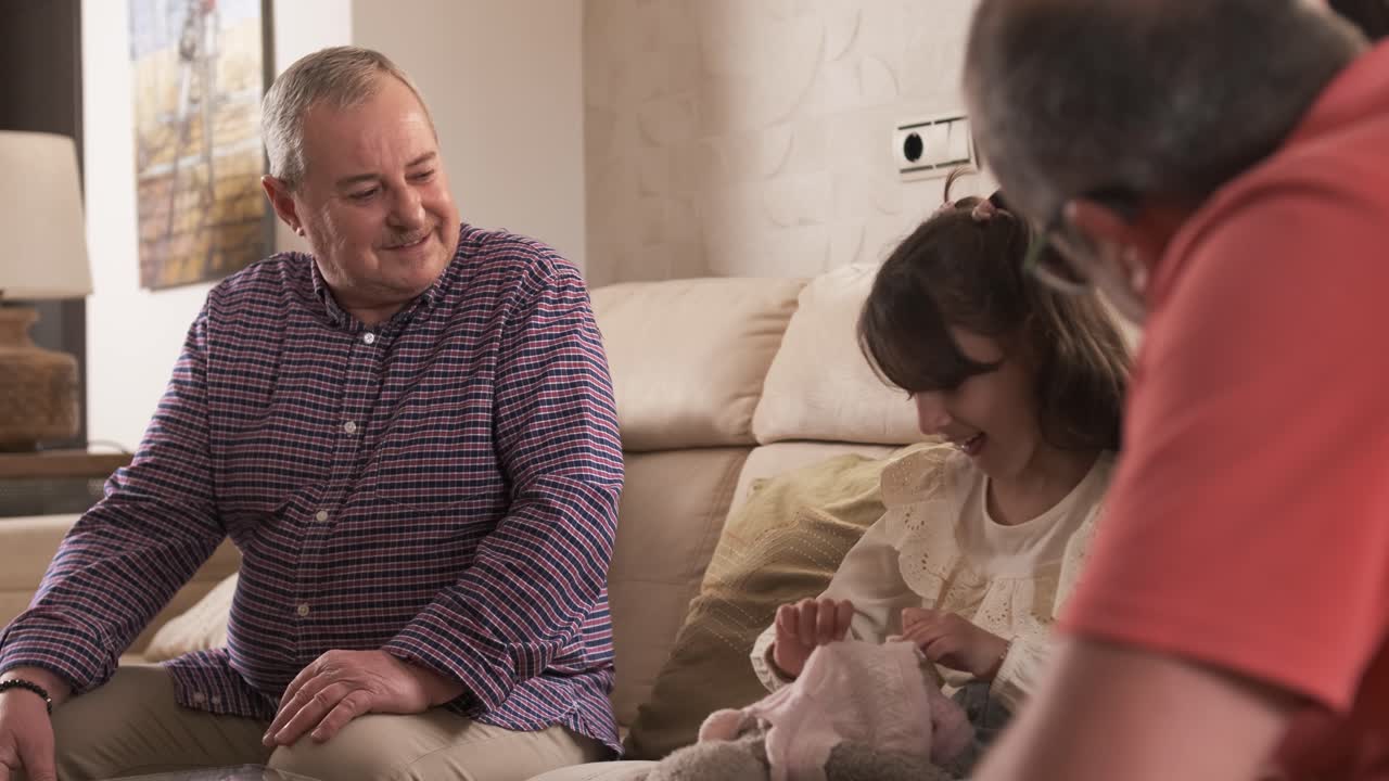 Girl talking with her grandparents sitting on a sofa