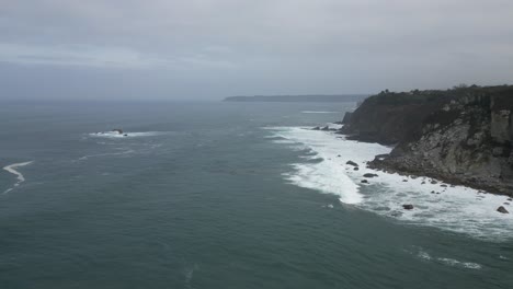 aerial drone shot of sea waves breaking on rocky mountains