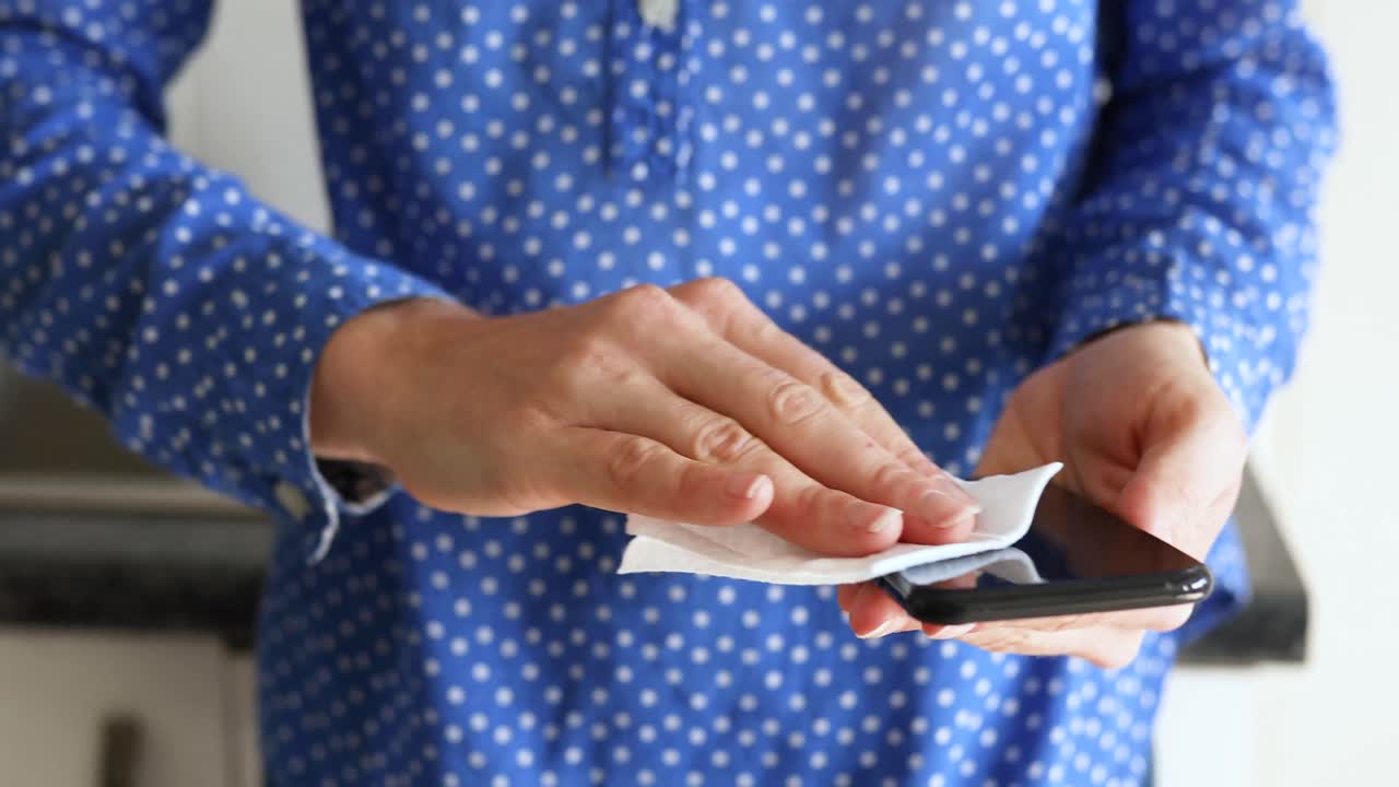 mujer caucásica lavando su teléfono en casa.