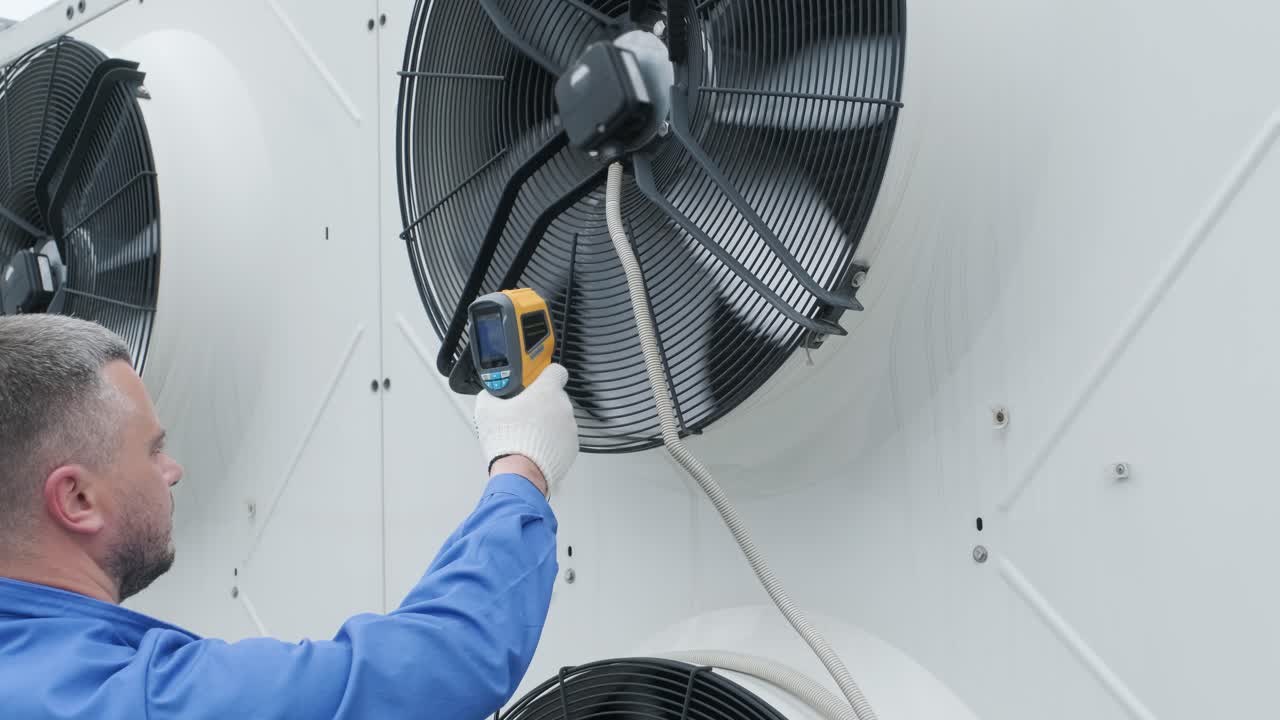 Technician uses a thermal imaging infrared thermometer to check the condensing unit heat exchanger