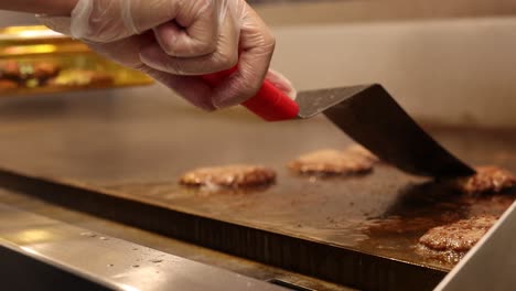 chef cooking burger meat using metal spatula