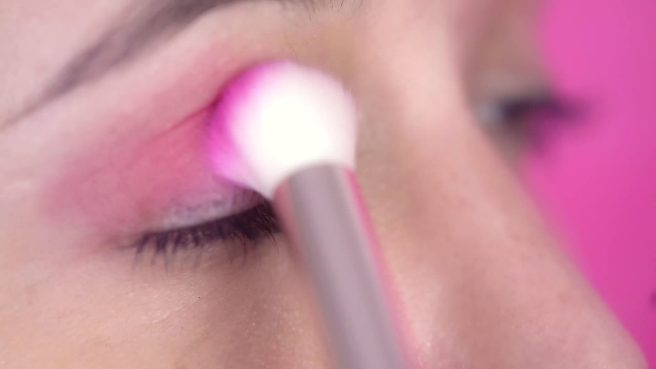 Close-up of Woman Applying Pink Eyeshadow with Makeup Brush