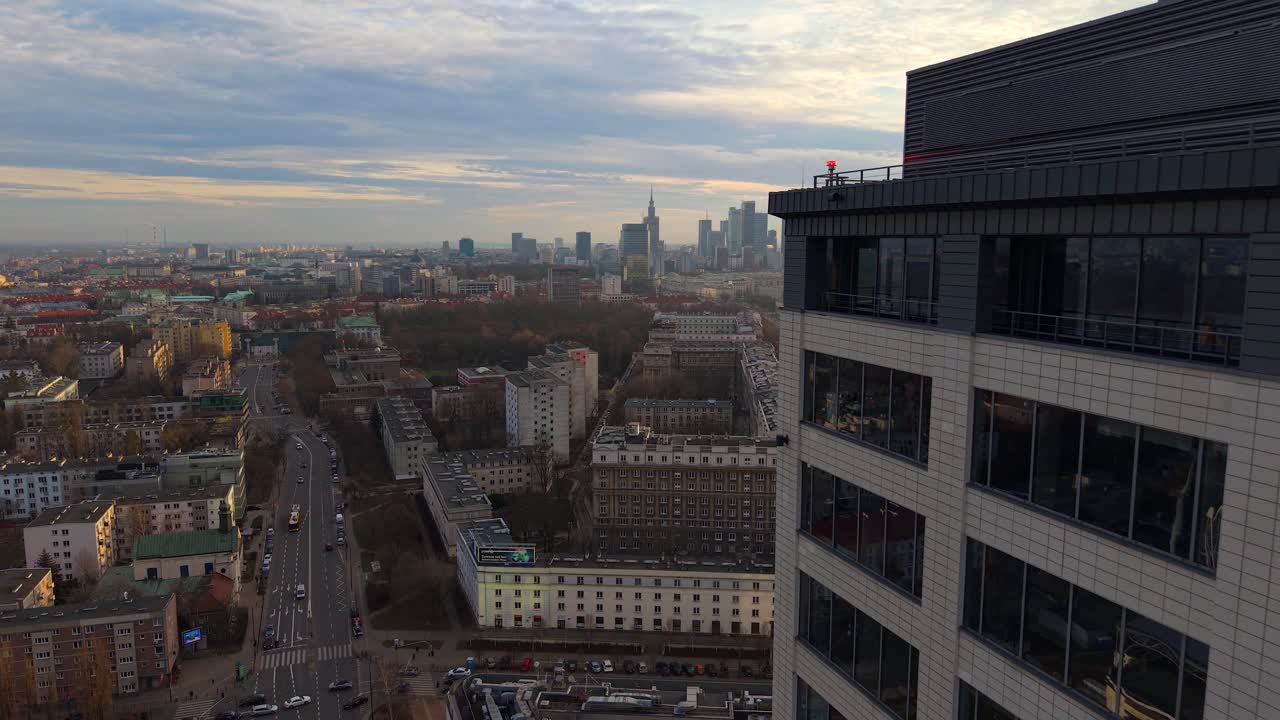 Aerial drone passing modern offices, revealing Warsaw city center and Muranow district, panoramic overview of streets at sunset