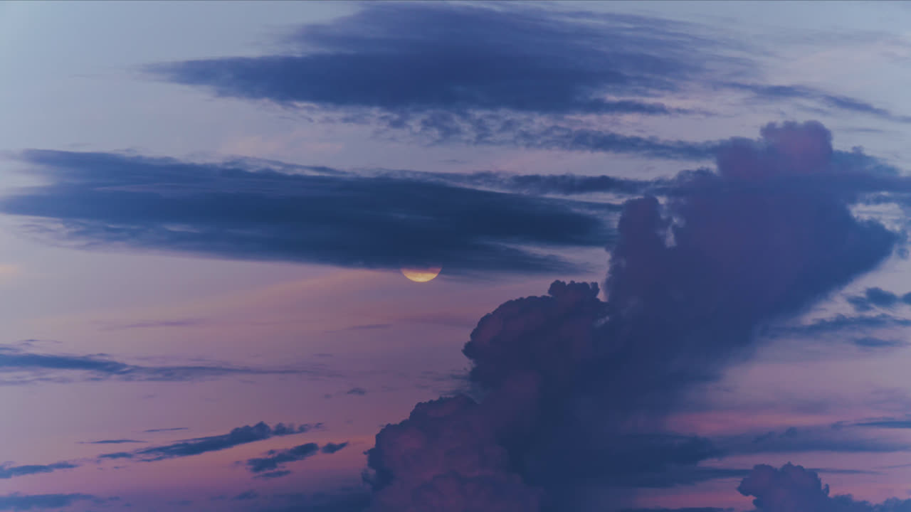 Una vista celeste mozzafiato di una luna piena luminosa parzialmente oscurata da un'enorme e imponente nuvola cumulonembo nel cielo crepuscolare