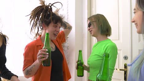 group of four happy girl friends drinking beer, talking and dancing at home 1