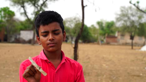 indian little boy standing with toy wind turbine in hand at summer. hq footage.