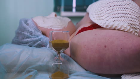 young woman with alginate mask on face and glass clock