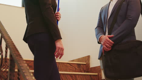 businesspeople standing on stairs discussing in office building