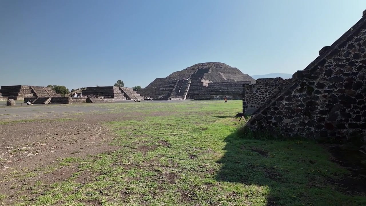 Ripresa ravvicinata di un viaggiatore che cammina verso la Piramide del Sole nel sito archeologico di Teotihuacan sotto un cielo azzurro e limpido in Messico.