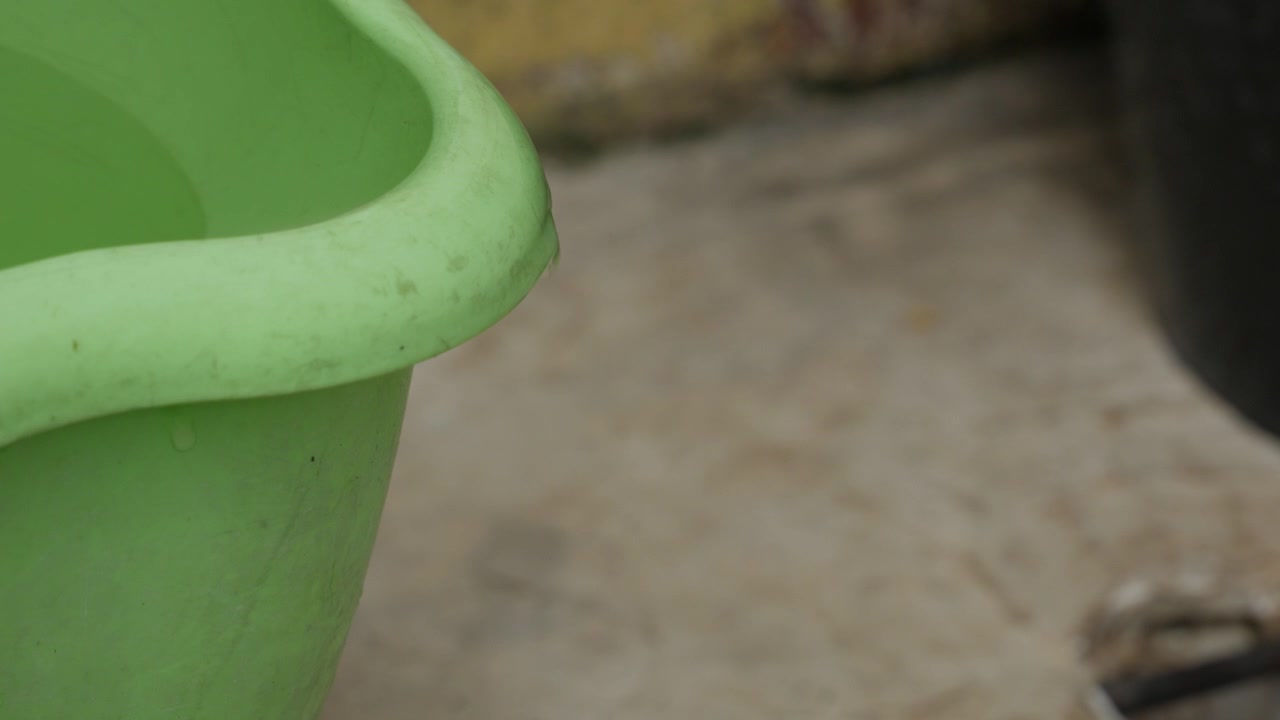 Water Dripping from the Rim of a Filled Plastic Bucket Close Up