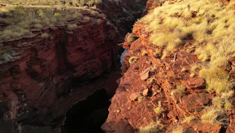 woman in the desert standing on the edge of the cliff in karijini in western australia, aerial orbital