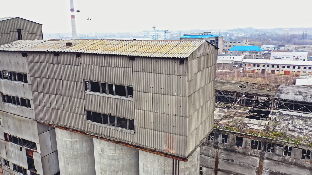 Flight over the empty old plant almost ruined in the city after the war. Old abandoned buildings without windows are broken-down. Camera moves around