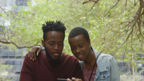 Couple-using-mobile-phone-in-outdoor-cafe-4k