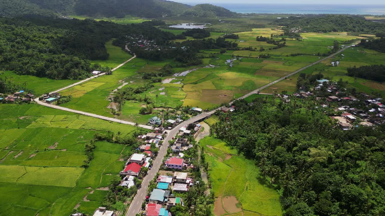High angle aerial ascend overview of Bato town buildings, roadways and forested hills in Catanduanes region Philippines