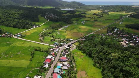 high angle aerial ascend overview of bato town buildings, roadways and forested hills in catanduanes region philippines