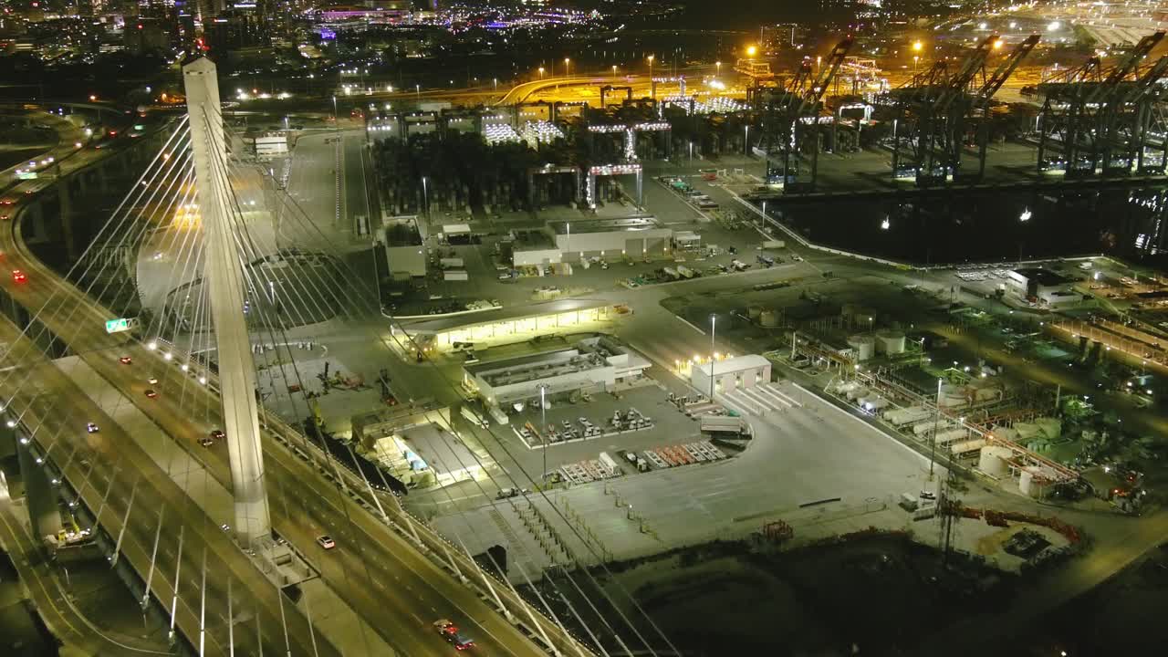 vuelo aéreo sobre el puente en long beach california | puerto de envío en el fondo | hora de la noche