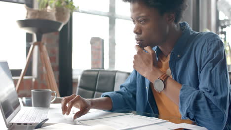 Focused-african-american-casual-businessman-sitting-at-desk-using-laptop-at-home,-slow-motion