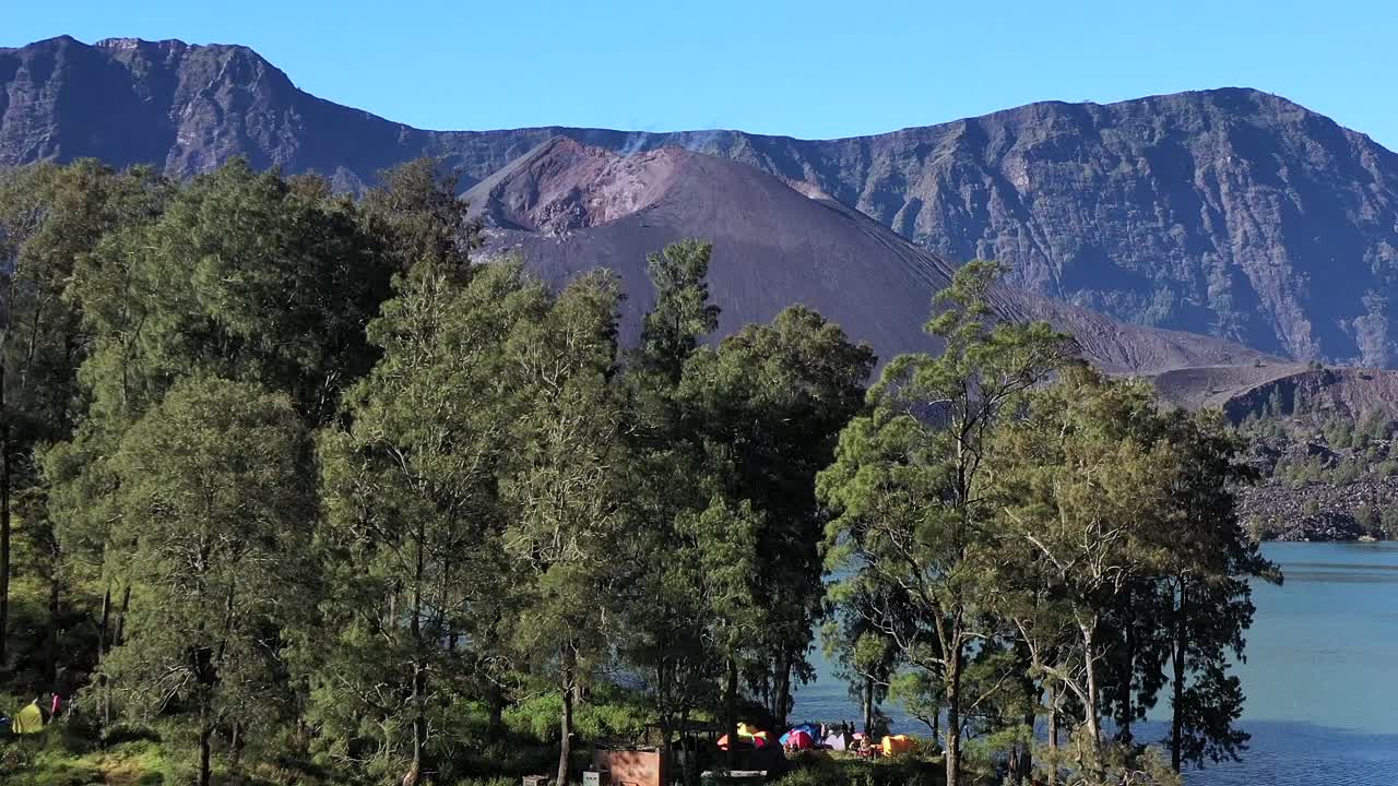 camping con carpas coloridas a orillas del lago del cráter del volcán monte rinjani indonesia, nusa tenggara, toma ascendente del pedestal aéreo