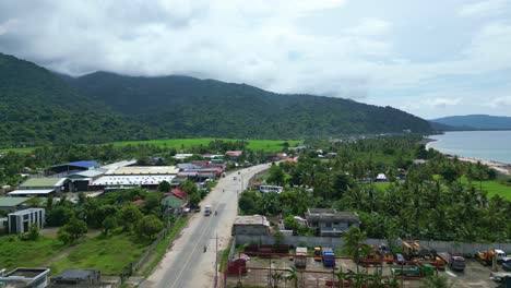 Aerial,-Overhead-Panning-Shot-of-Island,-Mountainous-Town-and-Busy-Street-then-revealing-an-Idyllic-Ocean