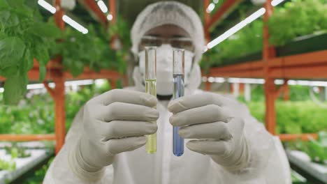 Young-Contemporary-Researcher-Or-Agroengineer-In-Protective-Workwear-Holding-Two-Flasks-With-Liquid-Substances