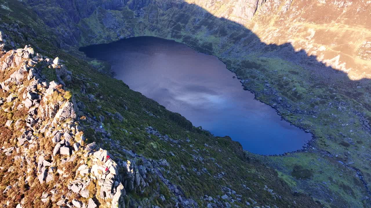 Episk bjergdroneoptagelse fra Irland viser klatrere på Coumshingaun South Ridge i Comeragh Mountains, Waterford, midt om vinteren