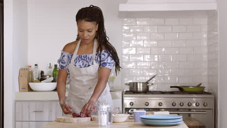 Vista-Frontal-De-Una-Mujer-Cortando-Ingredientes-En-La-Mesa-De-La-Cocina,-Filmada-En-R3d