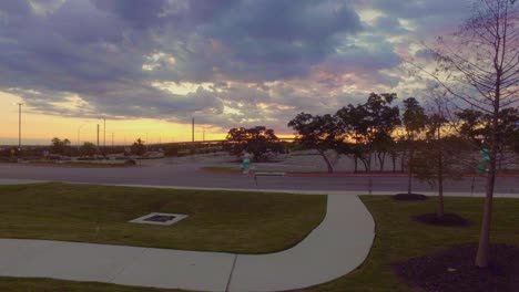 time laps of cars leaving apartments for work early morning commute with sunrise in the background and vacant car park ahead