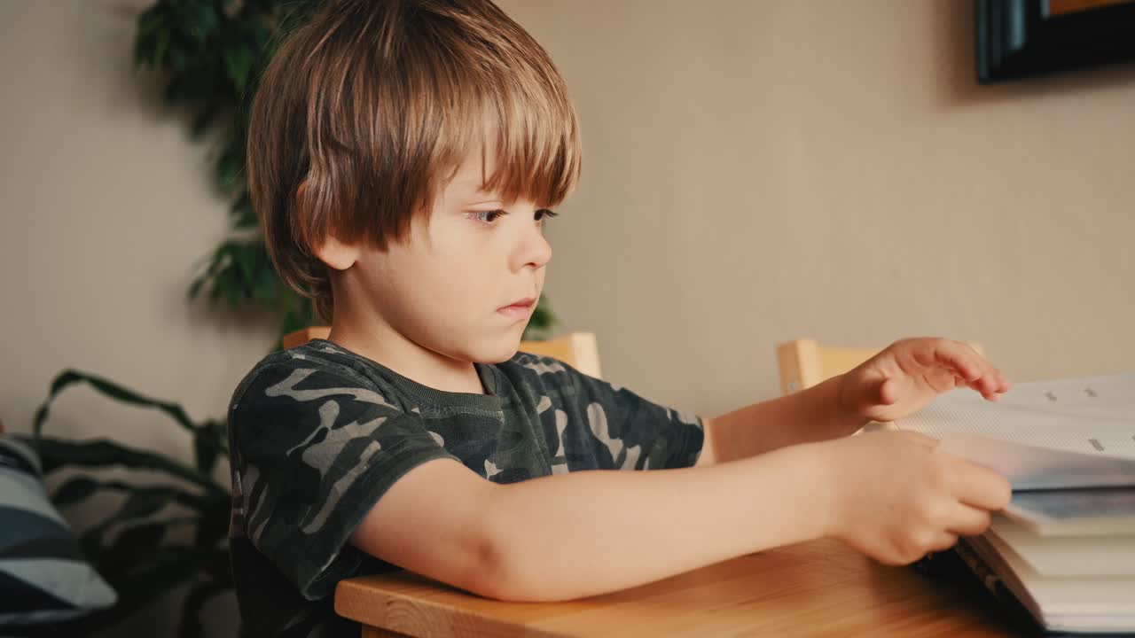 A young boy carefully turns pages in a photo album while sitting at a table. Focused and calm, he explores old family memories in a cozy home environment during a quiet moment.