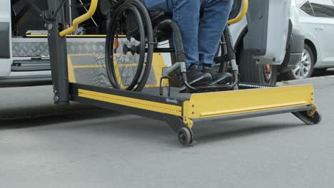 a man in a wheelchair on a lift of a vehicle for people with disabilities. lifting equipment for people with disabilities - man in wheelchair near the vehicle