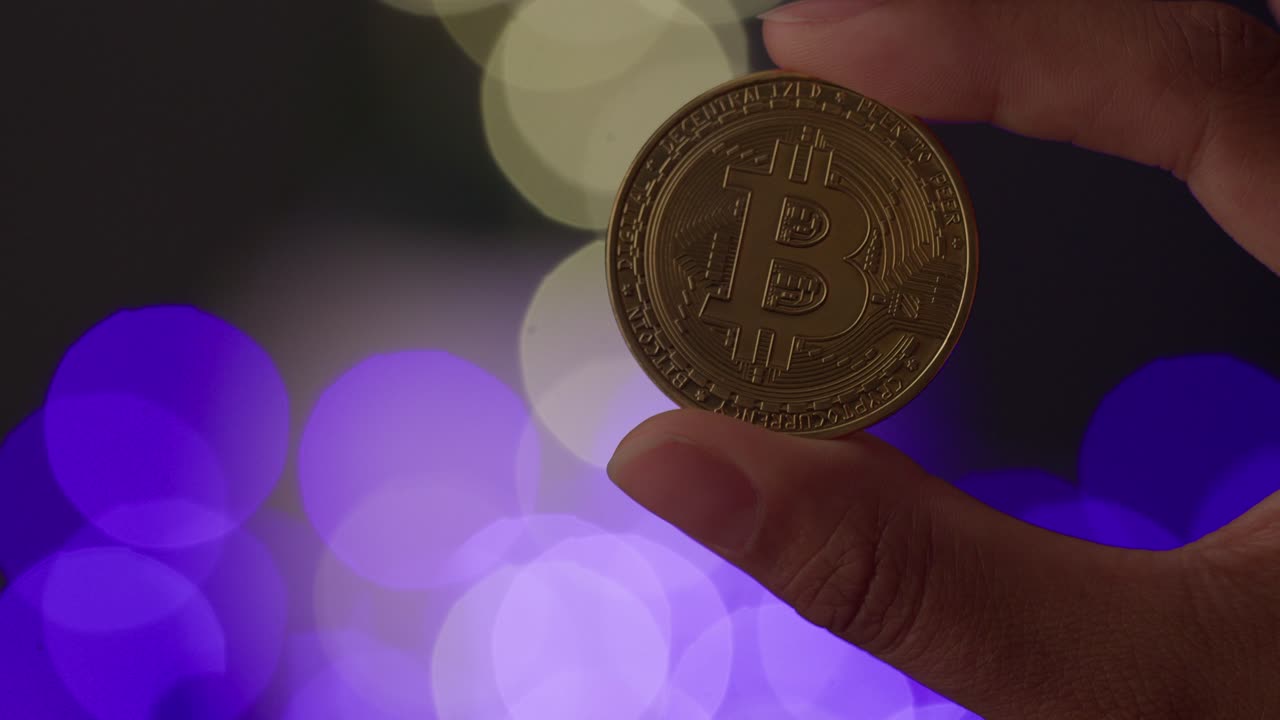 Ethereum, the smart contract crypto, held up by two fingers. 4K. Orange and blue bokeh balls in the background