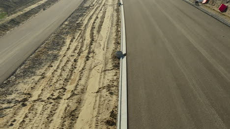 vista aérea cercana de una carretera recién pavimentada al lado de una pista de tierra