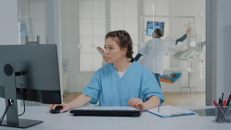 Enfermera-De-Odontología-Sentada-En-El-Escritorio-Escribiendo-En-El-Teclado-De-La-Computadora