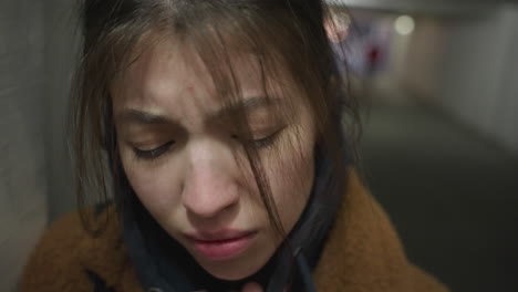 close-up shot of a heavy-hearted girl standing in an underpass tunnel. she looks deeply unhappy, with a distressed expression, and her hand partially covering her face, conveying emotional turmoil