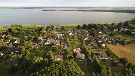 Aerial-view-from-Wieck-village-on-the-peninsula-Fischland-Darß-Zingst-in-sunset-light,-with-bodden-in-background