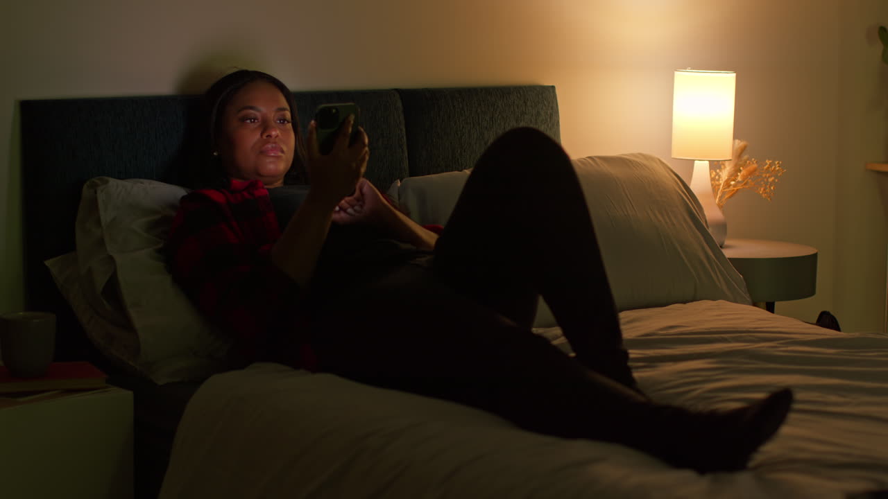 Woman using smartphone in bed at night