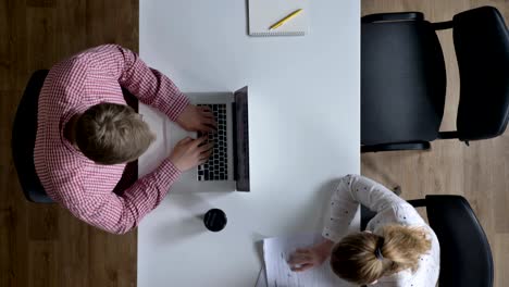 camera moving over business people working and sitting at table in modern office, topshot