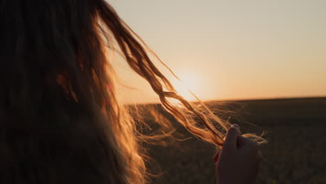 cute woman looks at her hair in the sun, holds a lock of hair in her hand