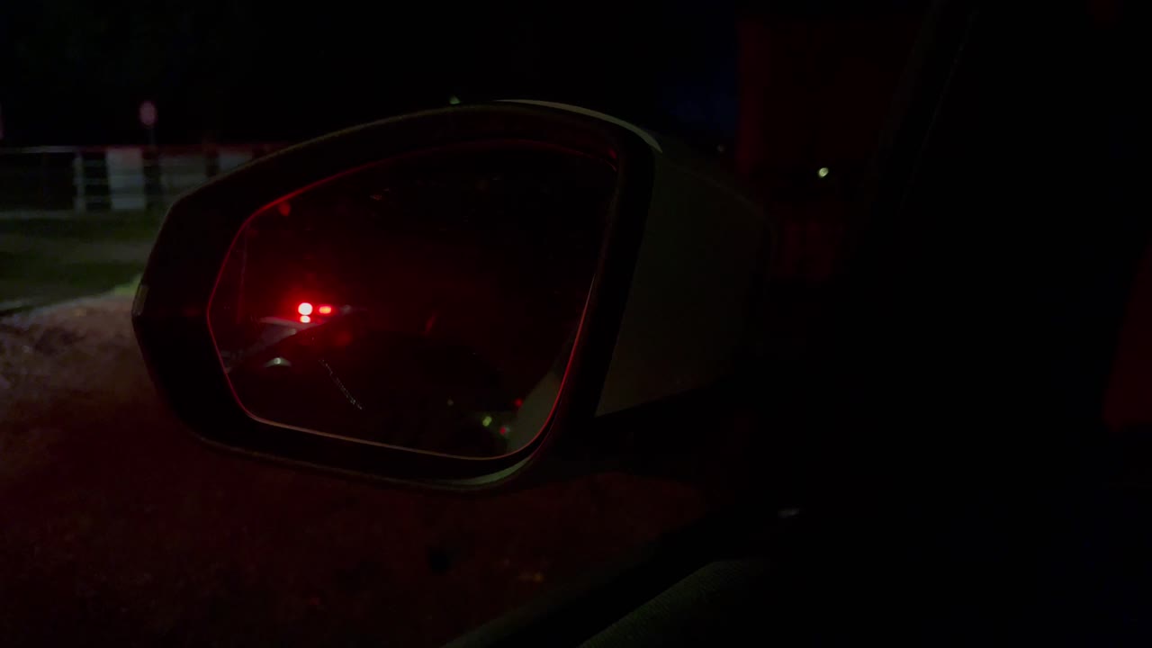 luces de policía parpadeando en la parte trasera o en el espejo retrovisor del coche, vista nocturna de cerca del reflejo de la baliza