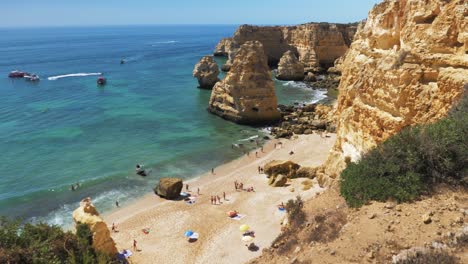 cámara lenta panorámica de la playa de marinha portugal durante el tiempo soleado con una pequeña cantidad de turistas tomando el sol
