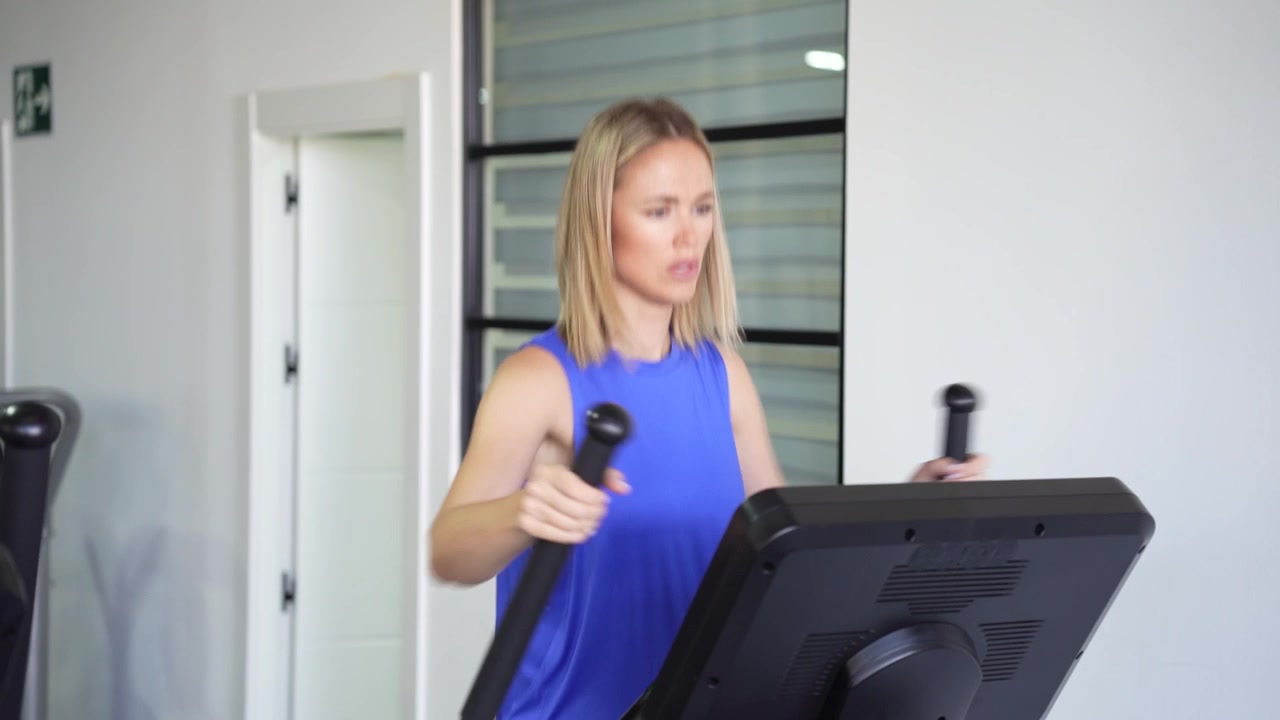 Una donna in palestra si allena con determinazione su un'ellittica per mantenersi in forma.