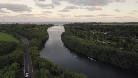 Dramatic-aerial-footage-of-famous-Wailua-River-during-sunset-with-people-on-canoes,-sunrise