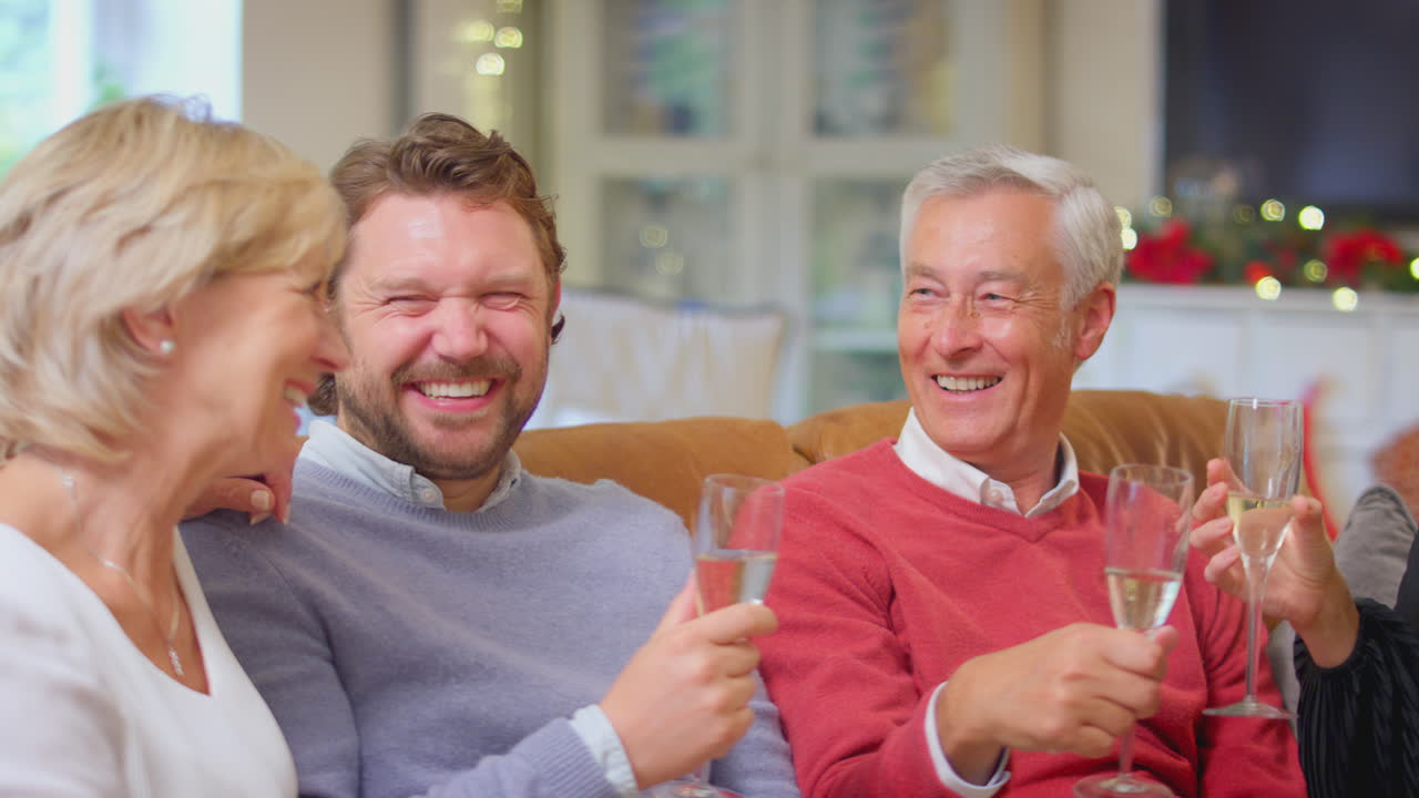 가정 에서 크리스마스 를 축하 하기 위해 페인 을 마시며 토스트 를 하는 소파 에 있는 노인 부모 와 함께 있는 부부