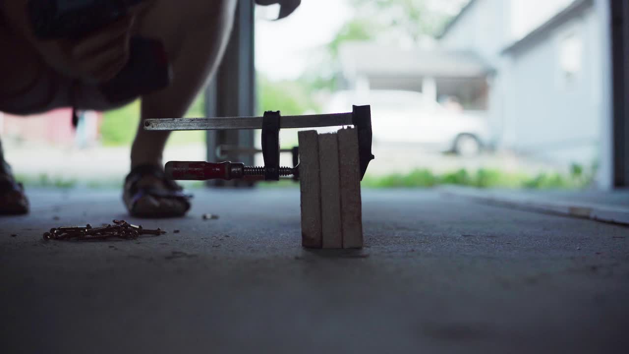 가게 안의 클램프에 나무 판을 스크루하는 남자의 절단된 전망