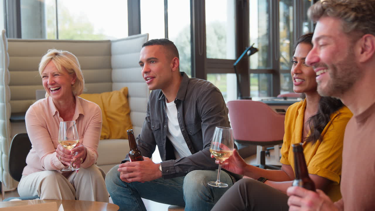 Staff At Informal Meeting In Office Making A Toast With Drinks After Work