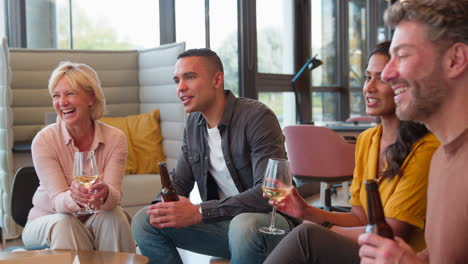 staff at informal meeting in office making a toast with drinks after work